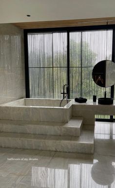 a large white bathtub sitting next to a window in a room with glass doors