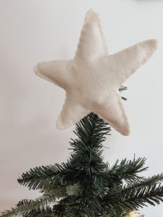 a white star ornament hanging from a christmas tree