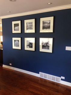 a room with blue walls and pictures on the wall above it, along with hardwood flooring