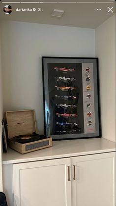 an old record player sitting on top of a white cabinet next to a framed poster