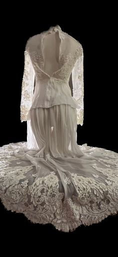 an antique white dress with lace on the bottom and sleeves, sitting on top of a doily