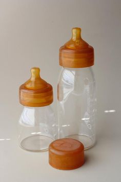 two glass baby bottles with lids are sitting next to each other