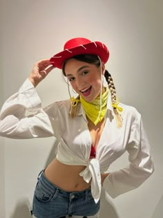 a woman wearing a red hat and bandana poses for the camera with her hands on her head