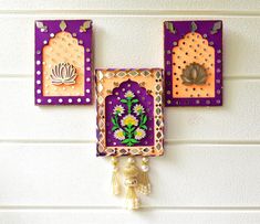 two colorful wall hangings with flowers and tassels on the side of a white wall