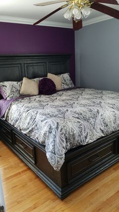 a large bed sitting in the middle of a room next to a wooden floor and ceiling fan