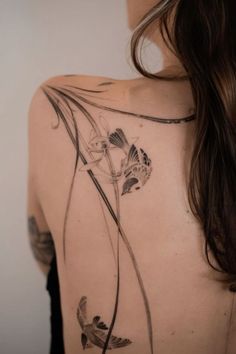 the back of a woman's shoulder with flowers and leaves on her left side