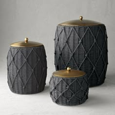 three black and gold canisters sitting on top of a white table next to each other