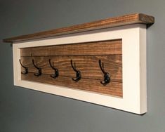 a wooden coat rack with hooks hanging from it's sides on a gray wall