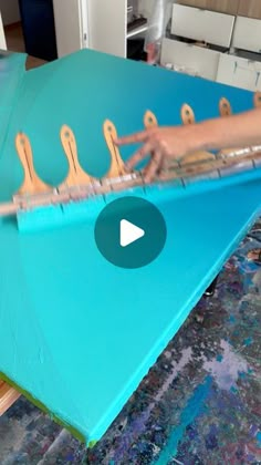 a person is playing an instrument on a blue sheet in the process of painting it