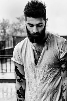 a bearded man with tattoos on his arms