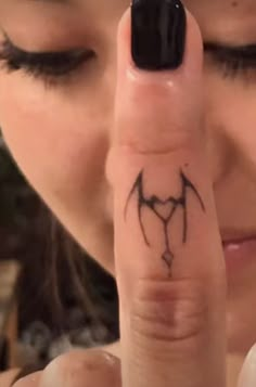 a woman pointing her finger at the camera with a bat tattoo on it's finger