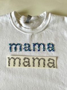 a t - shirt with the words mama on it, and an embroidered name tag