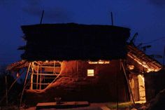 a hut lit up at night with lights on the roof and stairs leading to it