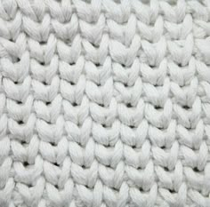 the texture of a white knitted blanket is shown in close - up, as if it were knitting or crocheting