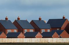 a row of red brick houses sitting next to each other on top of a grass covered field