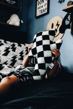 a woman laying on top of a bed holding a black and white checkered blanket