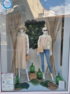 two mannequins dressed in clothes and hats are displayed behind a glass window