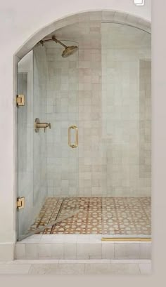 a bathroom with a walk in shower next to a white wall and tile flooring