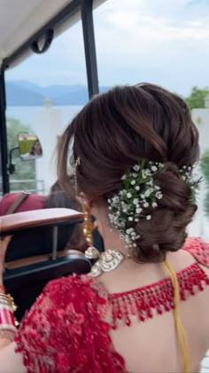 a woman with flowers in her hair sitting on a bus looking at the back of her head