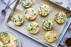 small muffins with spinach and cheese are on a baking sheet next to a fork