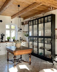 an old fashioned kitchen with lots of glass doors and shelves on the wall above it