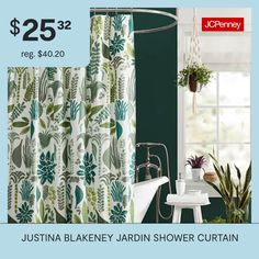 a bath tub sitting under a window next to a shower curtain with green leaves on it