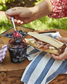 a person is eating a sandwich with blueberries and jam