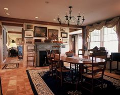 a dining room table and chairs in front of a fireplace with pictures on the wall