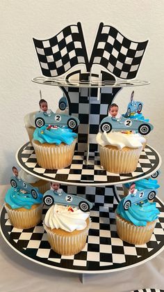 three cupcakes on a black and white checkerboard plate with race cars