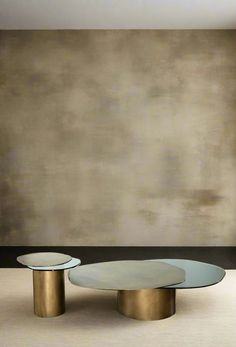 two round glass tables sitting in front of a wall