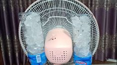 a pink fan sitting on top of a table next to two ice packs and water bottles