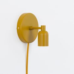 a yellow wall light on a white wall next to a plugged outlet in the shape of a lamp