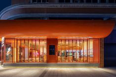 an orange building lit up at night with lights on the front and side windows that are open