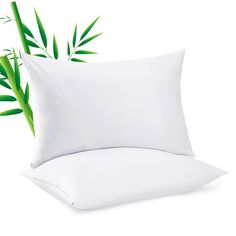 a white pillow and some green plants on a white background