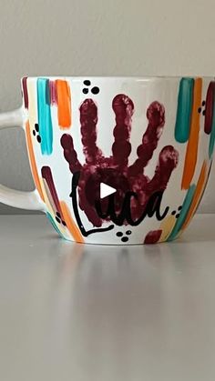 a coffee cup with handprints on it sitting on top of a white table