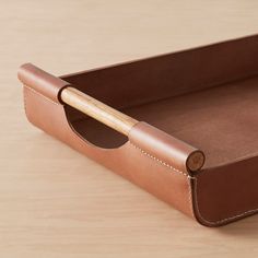 a brown leather box with a wooden handle