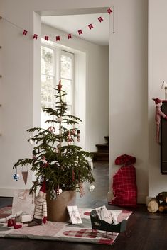 a small christmas tree in a pot on the floor next to other decorations and presents