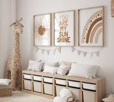 a nursery room with three pictures on the wall and two stuffed animals hanging above it