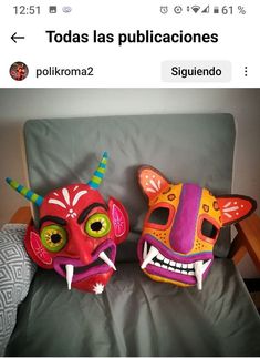 two colorful masks sitting on top of a couch