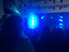 a group of people standing in front of a stage with lights on the side of it