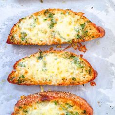 three pieces of bread with cheese and spinach on them sitting on a piece of parchment paper