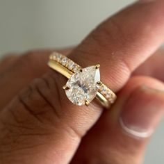 a woman's hand holding an engagement ring with a pear shaped diamond on it