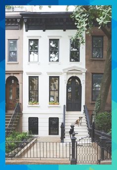 two story brownstone home with black wrought iron fence