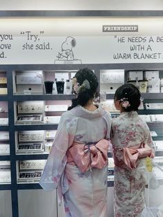 two women in kimonos are looking at the products on display behind glass cases