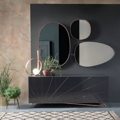 a black and gold sideboard with three mirrors on the wall next to potted plants