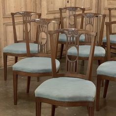 a set of eight chairs with blue upholstered back and seat cushions in front of wooden paneled walls