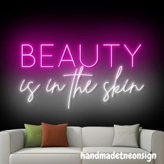 the words beauty is in the skin are lit up against a black background with a white couch