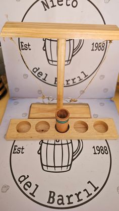 a wooden stand with three holes in it and a cup on the top that says nieco