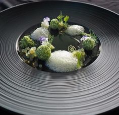 a black plate topped with broccoli covered in white stuff