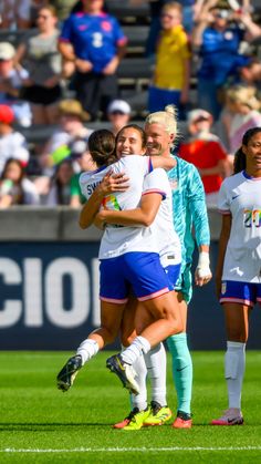 two female soccer players hugging each other on the field